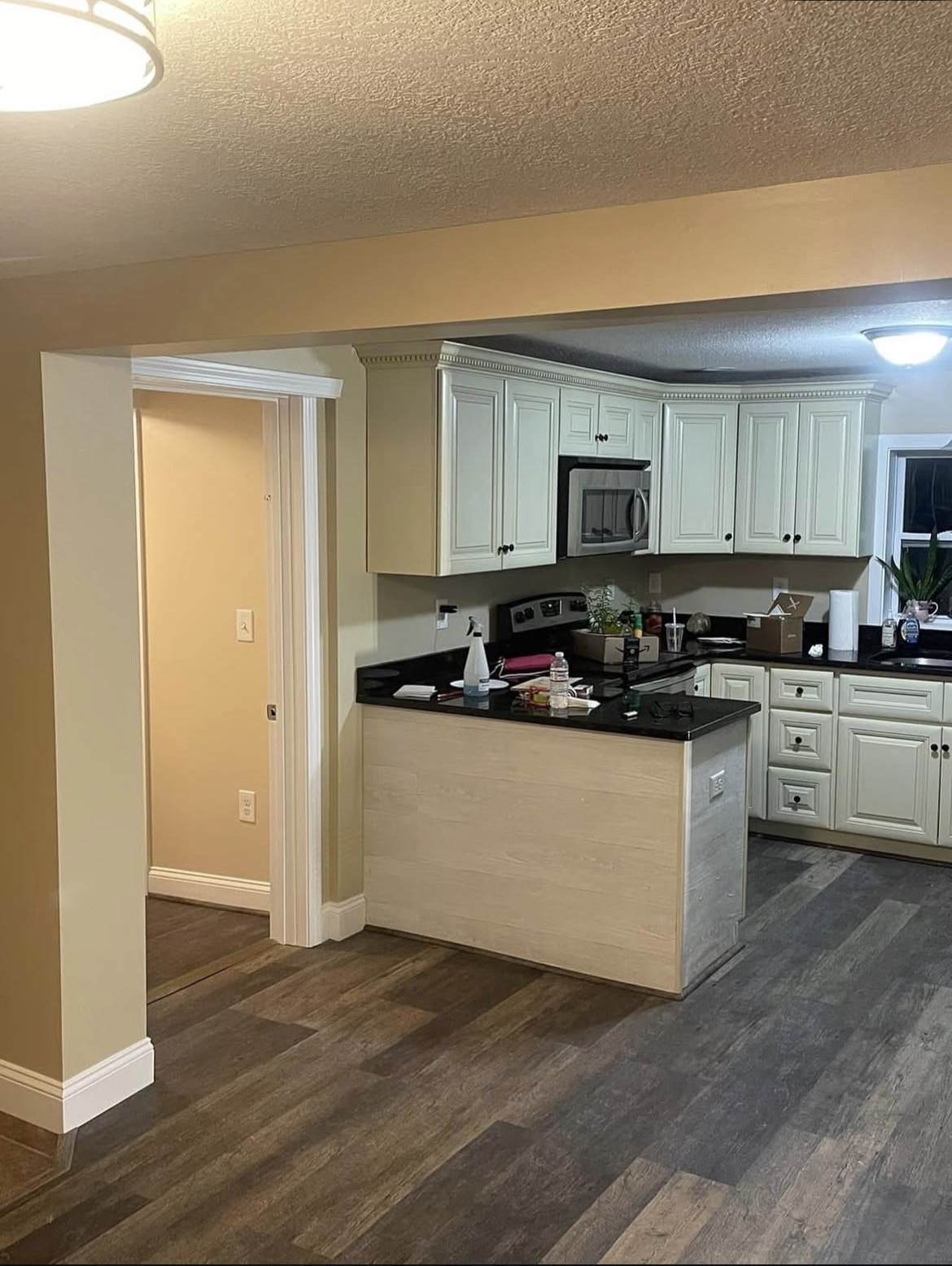 Kitchen and dining area with tan walls and white cabinets before repainting
