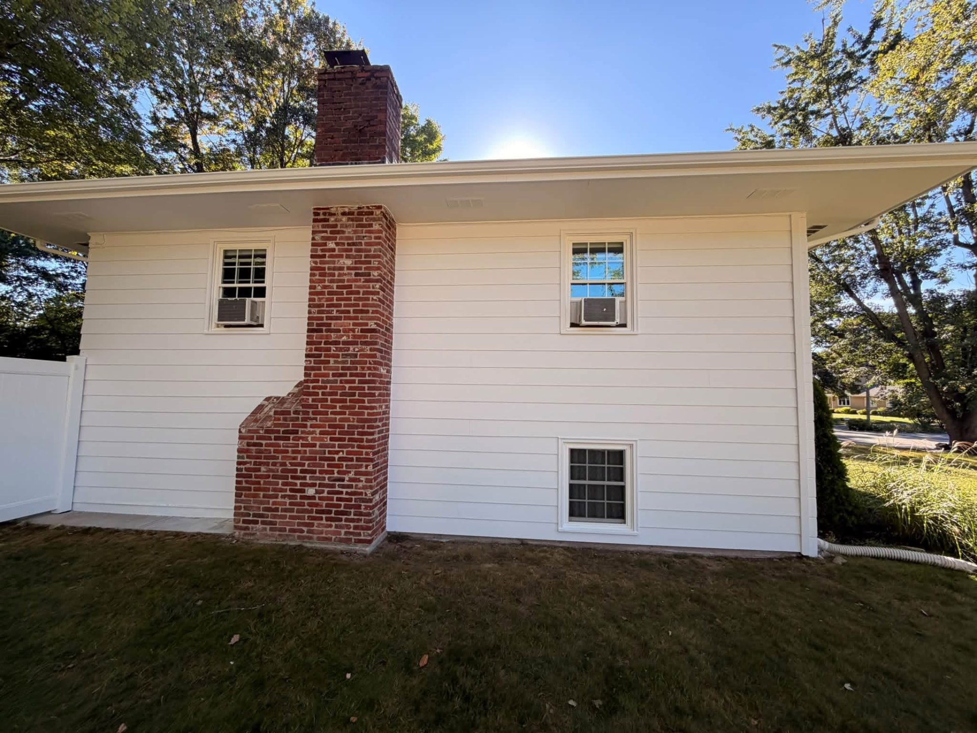 Freshly painted white house exterior with a red brick chimney