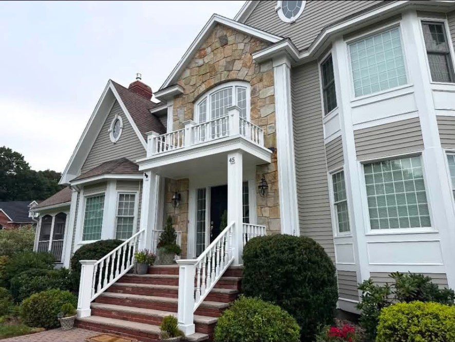 Painted siding and crisp white trim around a stone front entry with a white balcony