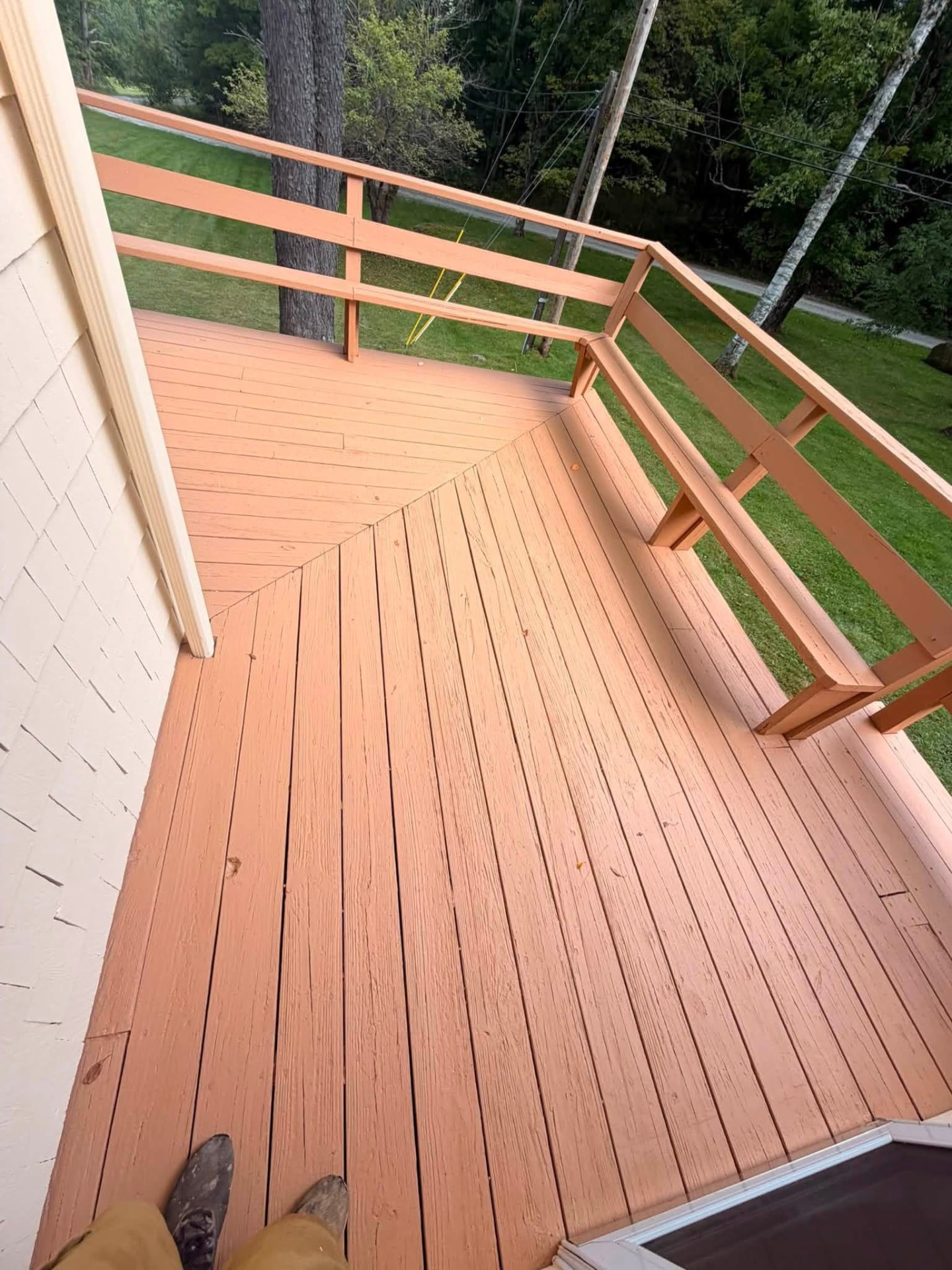 Stained deck boards and railings freshly coated and overlooking a backyard