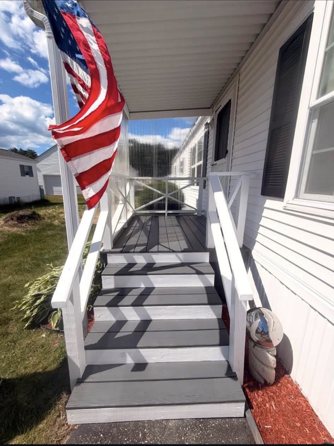 Front porch and entry stairs freshly painted with gray treads and crisp white risers and railings