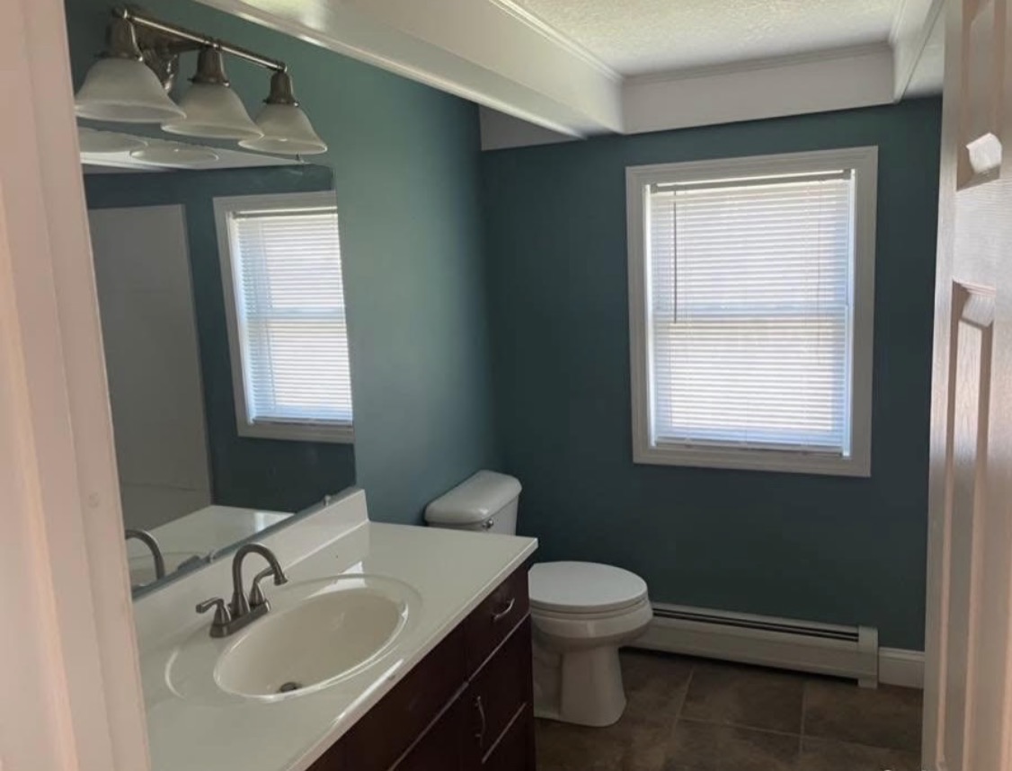 Same bathroom freshly painted in a deep teal with crisp white trim and ceiling