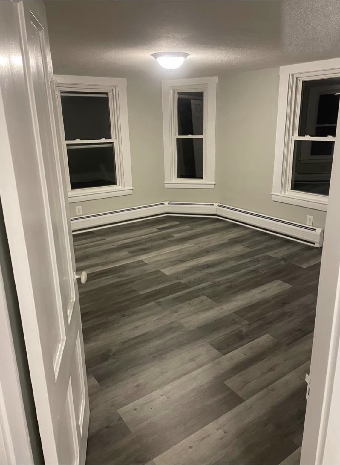 Same room with new gray wood-look flooring, freshly painted gray walls and crisp white trim