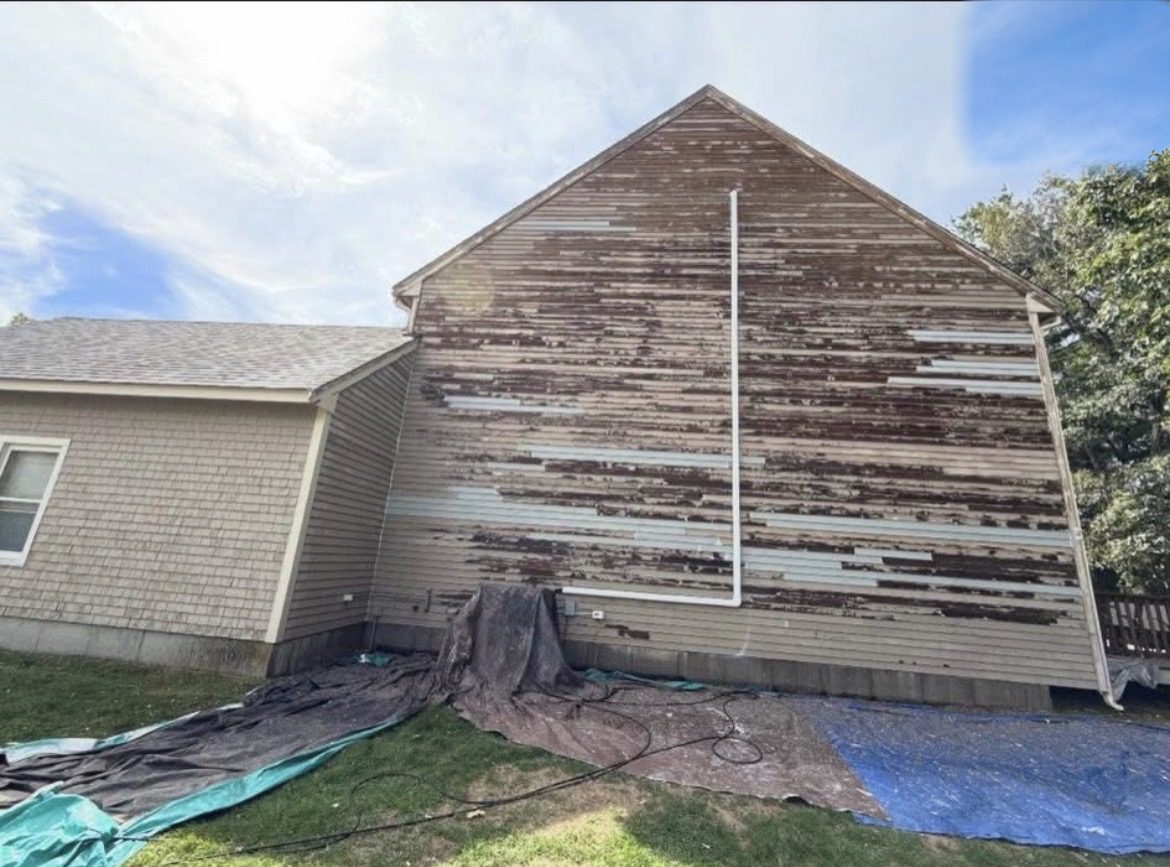 Gable end with heavily peeling, weathered siding and patch planks in place before replacement