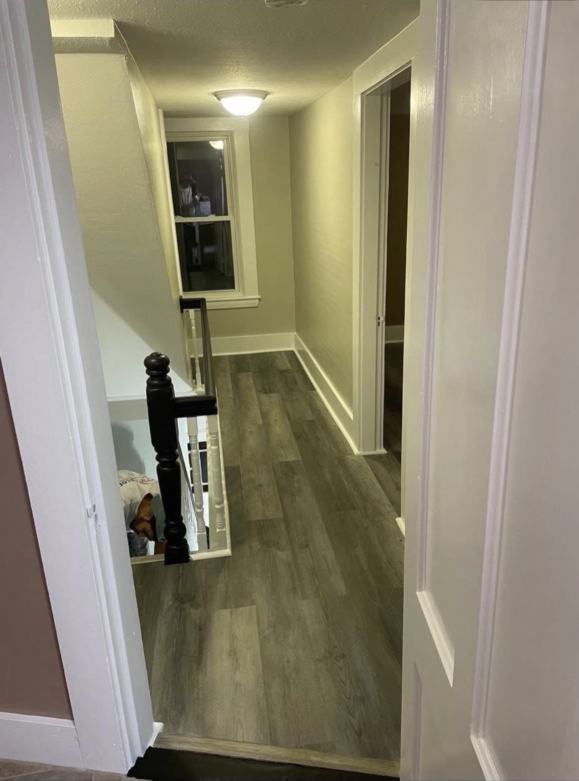 Same hallway with new gray wood-look flooring, freshly painted walls and crisp white trim and doors