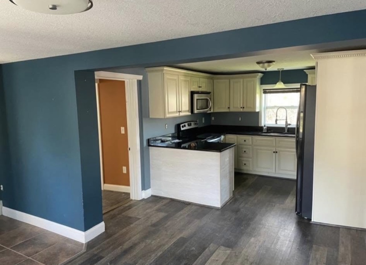 Same kitchen and dining area freshly painted in a deep blue with white trim and cabinets
