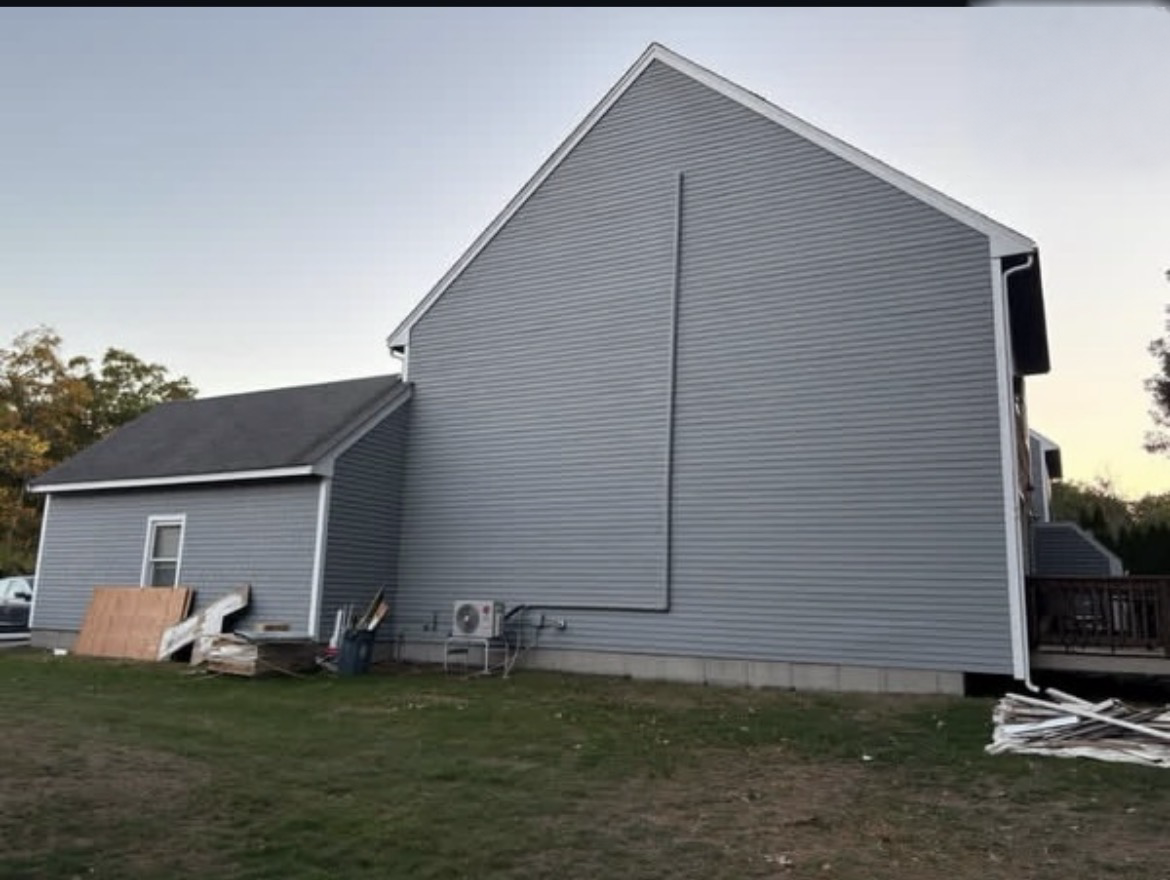 Same gable end with new gray siding and freshly painted white fascia, rake and corner trim