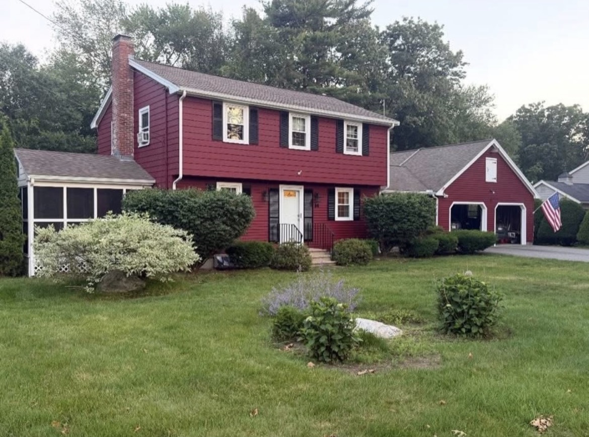 Same home freshly painted deep barn red with white trim, black shutters and a painted garage door